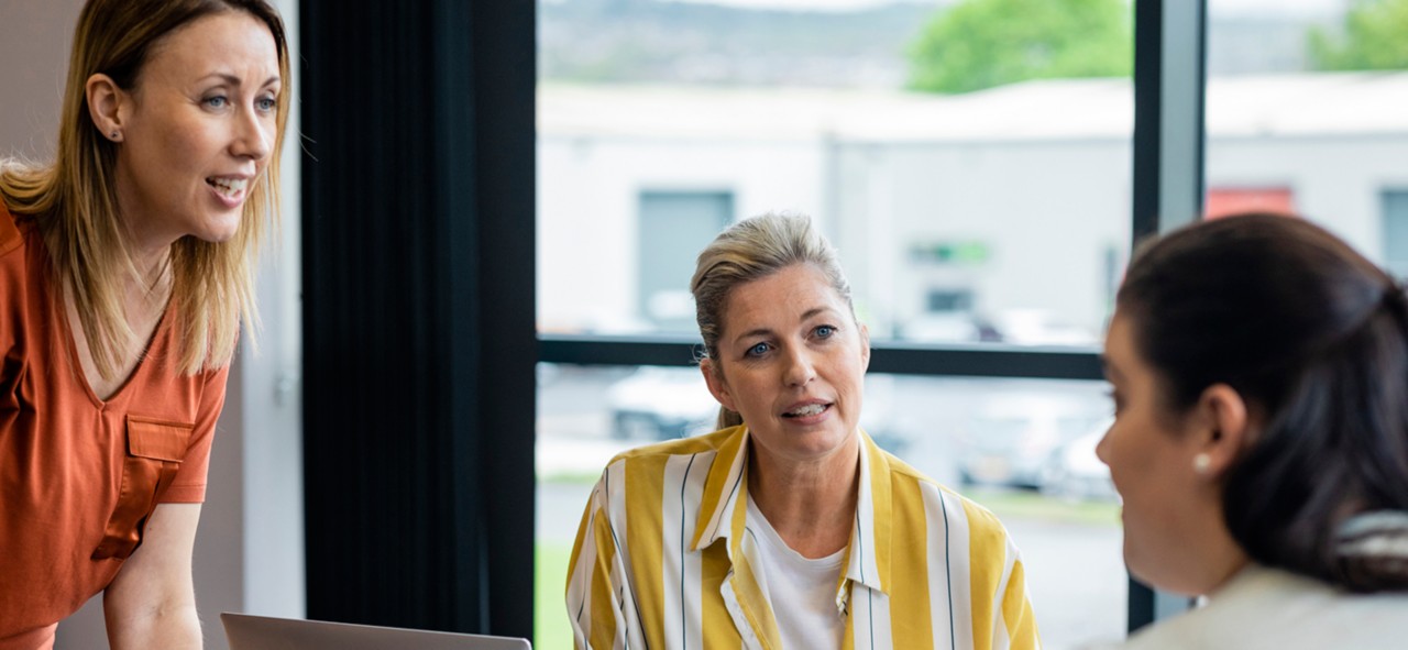 An over-the-shoulder view of a group of female managers having a meeting in the boardroom of their place of work in Hexham in the North East of England.