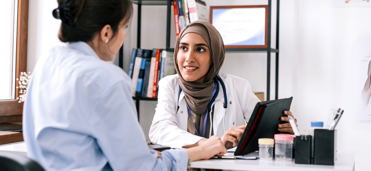Close up of a young Caucasian woman having an Asian doctor's appointment at medical clinic.