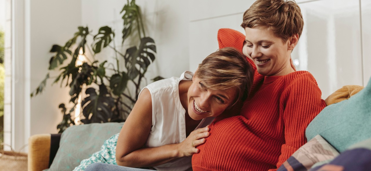 Happy lesbian couple feeling movements of baby belly of the expectant mother