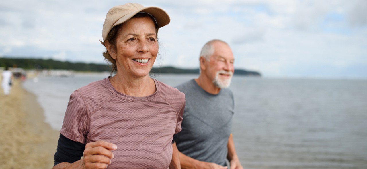 Active senior woman and man running outdoors sea.