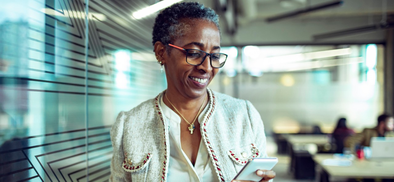 Close up of a senior businesswoman using a phone while having coffee in the office