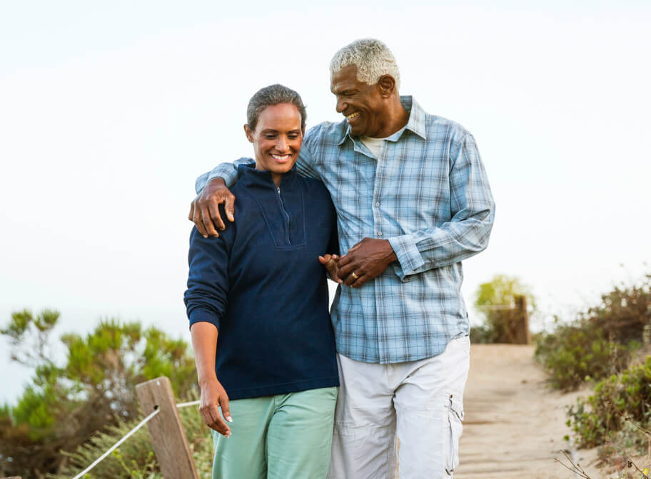 A senior couple walking outdoors and hugging.